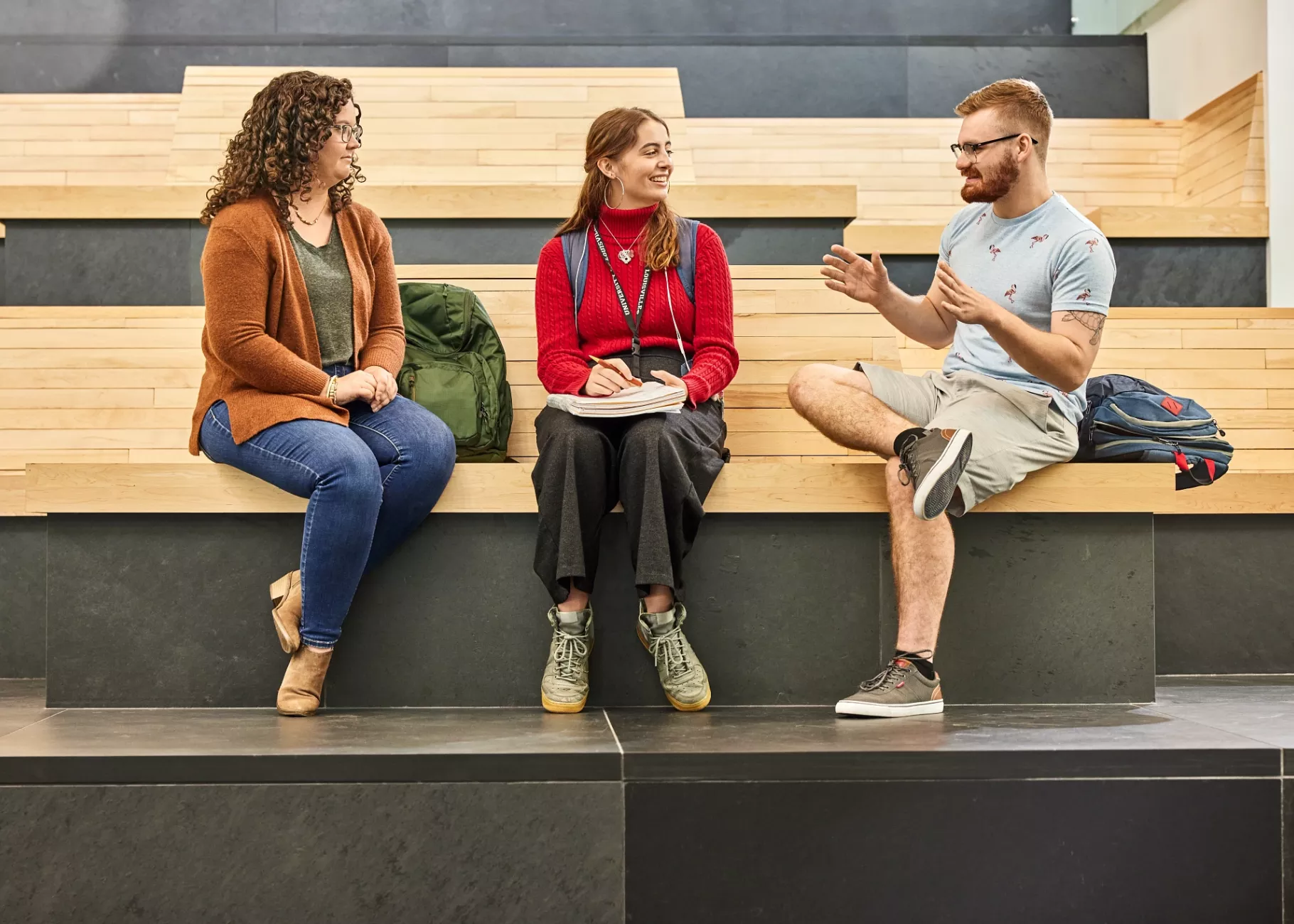 Alison Williams sitting on the wooden benches within the entrance of the Belknap Academic Building