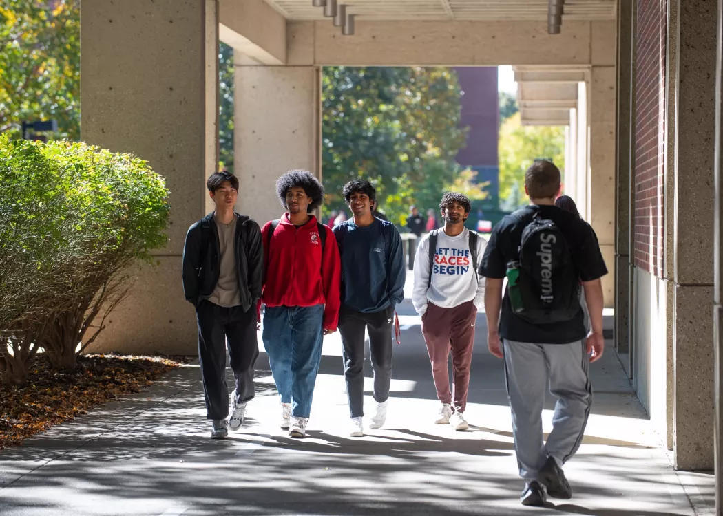 Group of students walking next to the Bingham Humanities building in the fall.